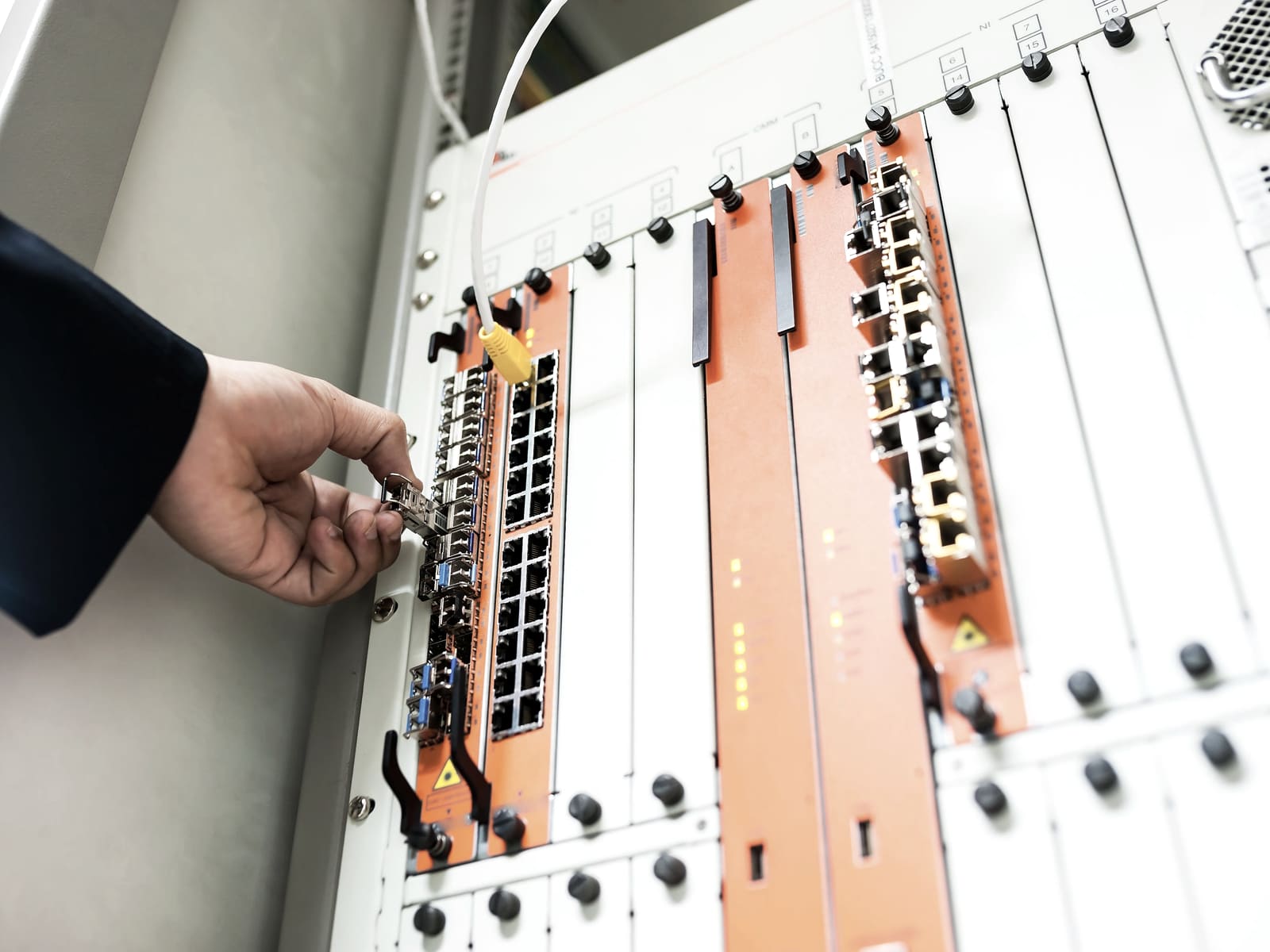 Mano di un tecnico che interviene su un apparato di rete in armadio